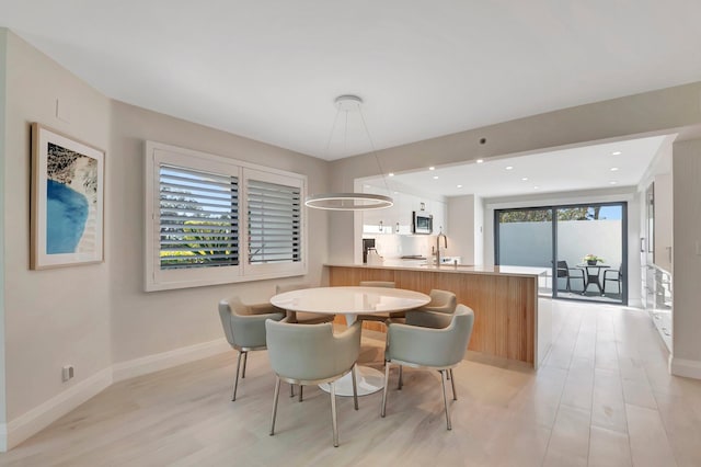 dining space featuring sink and light wood-type flooring