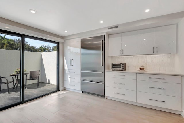 kitchen featuring white cabinetry, built in refrigerator, and backsplash