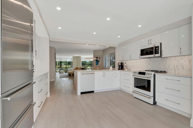 kitchen featuring white appliances, light hardwood / wood-style flooring, white cabinetry, backsplash, and kitchen peninsula