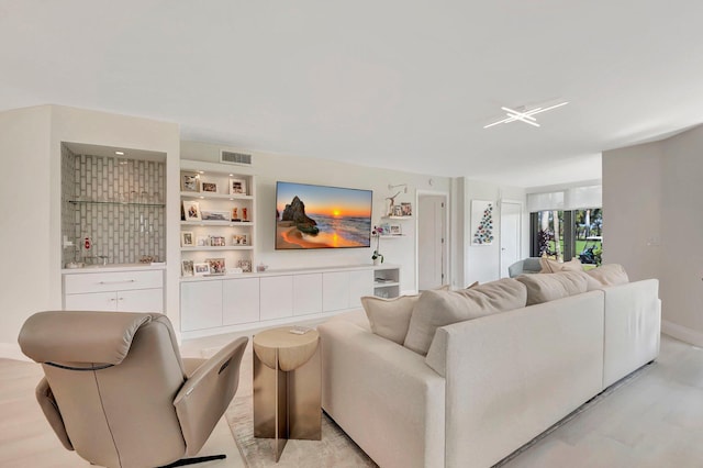 living room featuring built in features and light wood-type flooring