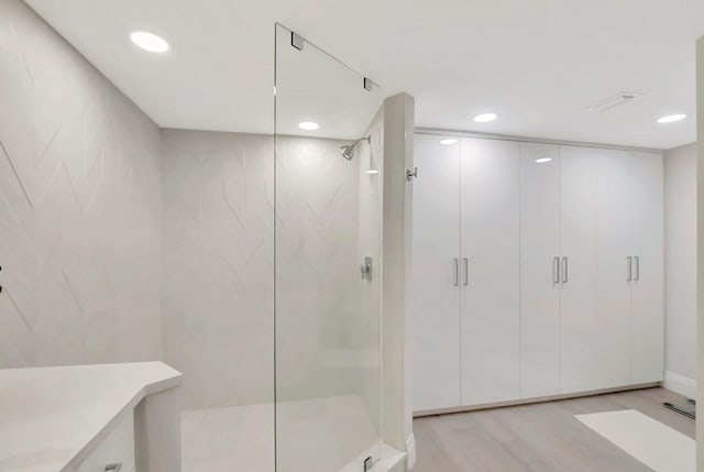 bathroom with wood-type flooring, vanity, and walk in shower