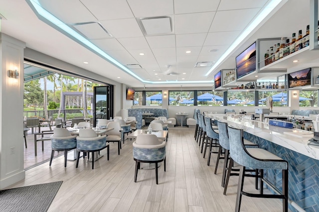 dining room with light hardwood / wood-style floors and a drop ceiling