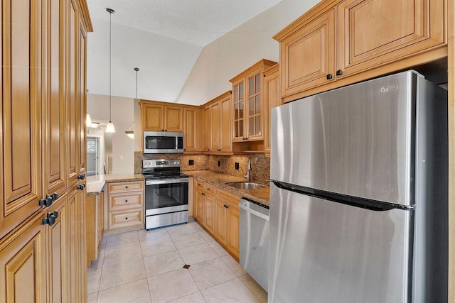 kitchen featuring lofted ceiling, sink, light stone counters, appliances with stainless steel finishes, and backsplash