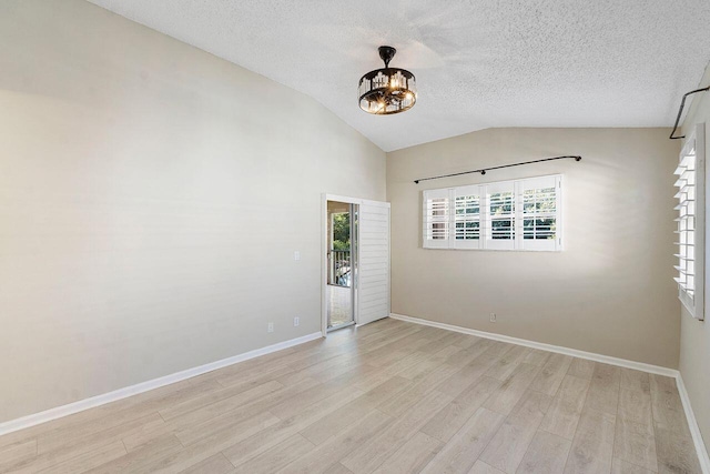 unfurnished room featuring lofted ceiling, light hardwood / wood-style floors, and a textured ceiling