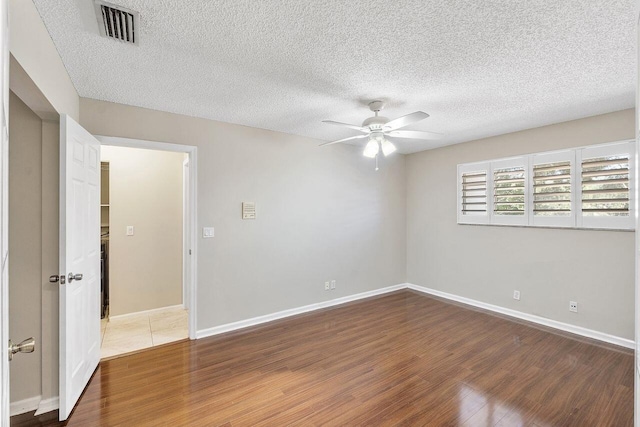 empty room featuring a textured ceiling, wood-type flooring, and ceiling fan