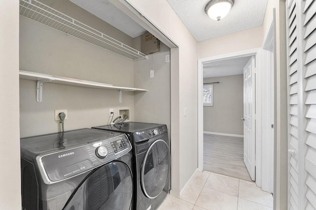 laundry room featuring light tile patterned floors, independent washer and dryer, and a textured ceiling