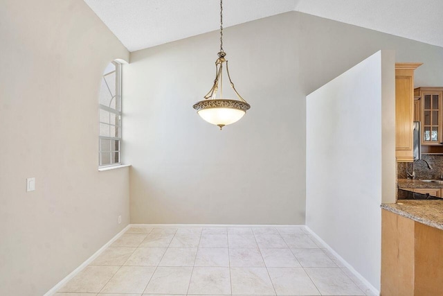 unfurnished dining area featuring lofted ceiling, sink, and light tile patterned flooring