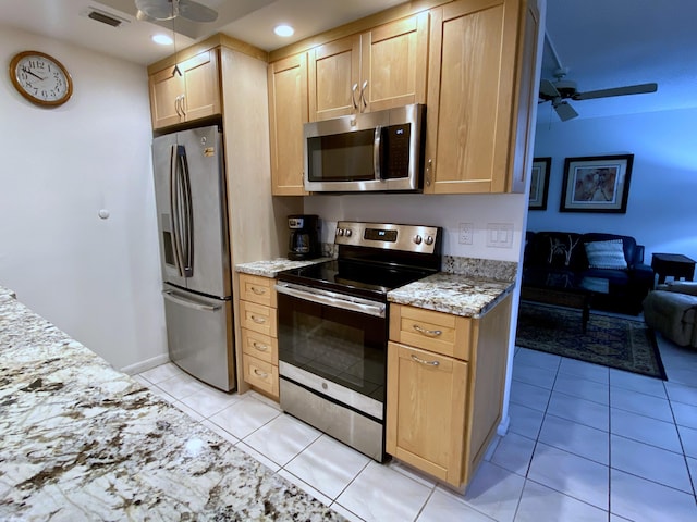 kitchen featuring ceiling fan, stainless steel appliances, light stone countertops, light tile patterned flooring, and light brown cabinets