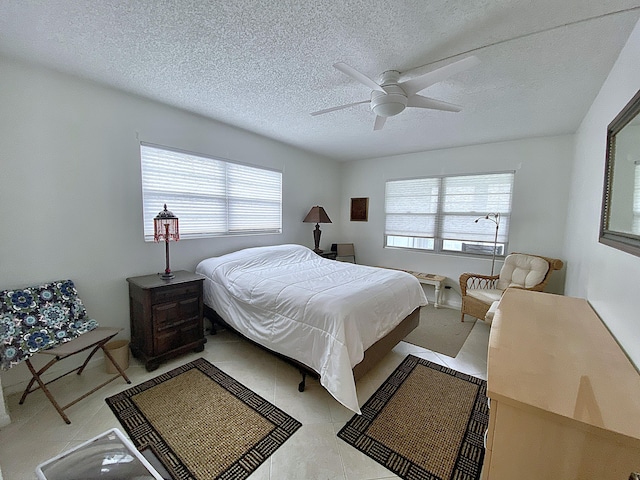 bedroom featuring a textured ceiling, a ceiling fan, and tile patterned floors