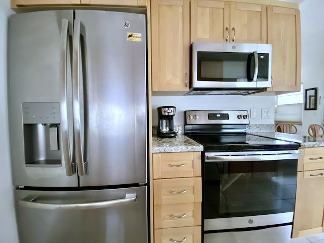 kitchen featuring light brown cabinetry, light stone counters, and appliances with stainless steel finishes