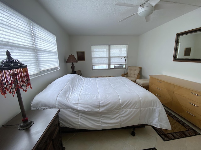 bedroom with a textured ceiling, ceiling fan, and tile patterned flooring