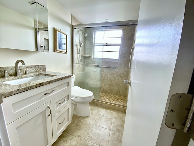 bathroom with tile patterned flooring, walk in shower, vanity, and toilet