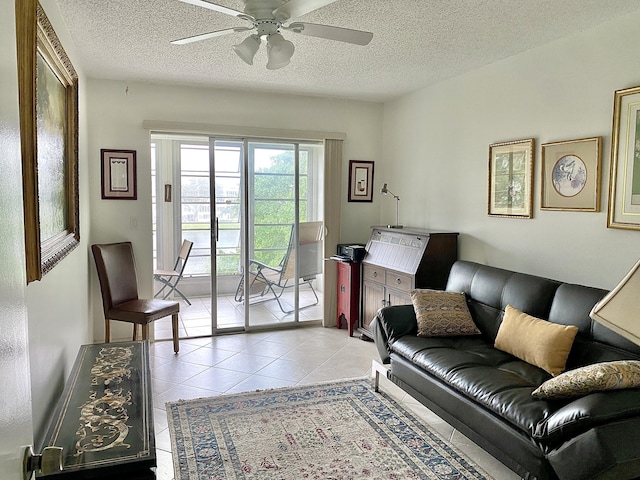 living room with light tile patterned flooring, ceiling fan, and a textured ceiling