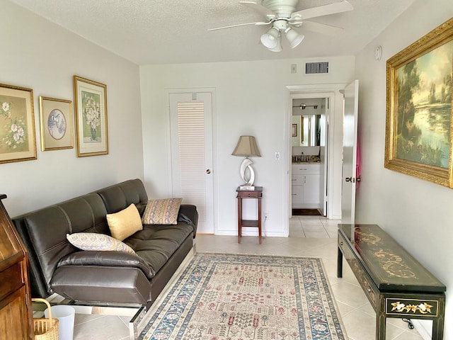 living room with ceiling fan, sink, a textured ceiling, and light tile patterned flooring