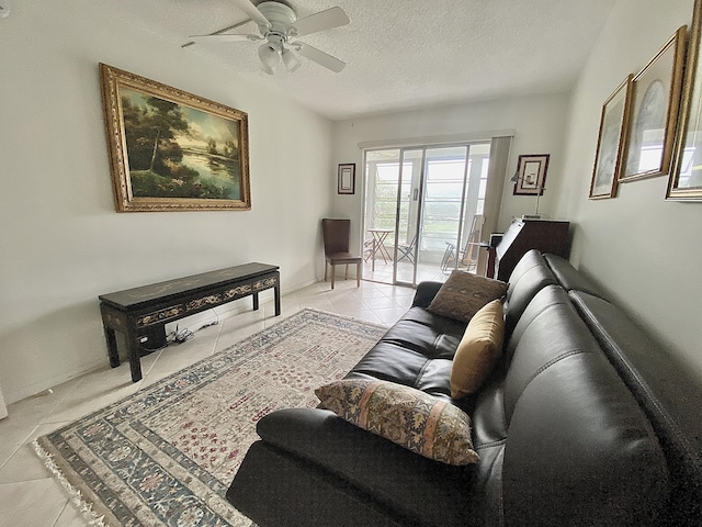 living room with ceiling fan, a textured ceiling, and light tile patterned floors