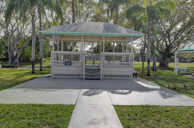 view of community with a deck, a gazebo, a lawn, and concrete driveway