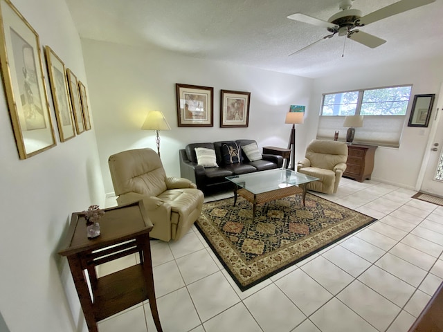 living room featuring light tile patterned flooring, ceiling fan, and a textured ceiling