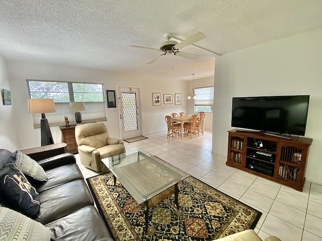 tiled living room featuring ceiling fan, a textured ceiling, and a wealth of natural light