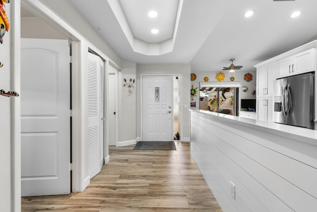 corridor with a tray ceiling and light hardwood / wood-style flooring