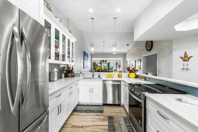 kitchen featuring white cabinetry, stainless steel appliances, light stone countertops, and sink