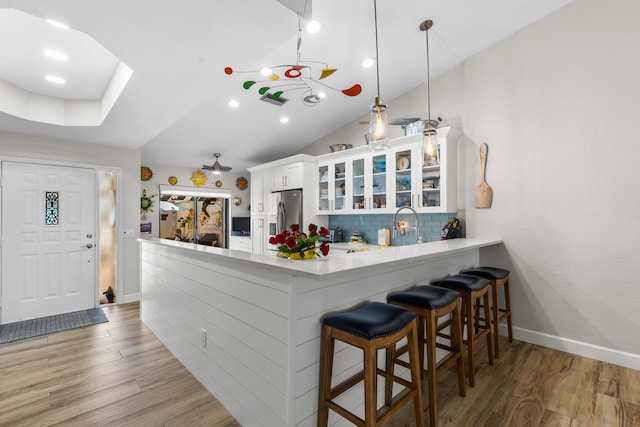 kitchen featuring white cabinetry, stainless steel fridge with ice dispenser, decorative light fixtures, and kitchen peninsula