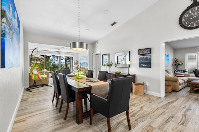 dining area featuring high vaulted ceiling and light hardwood / wood-style floors