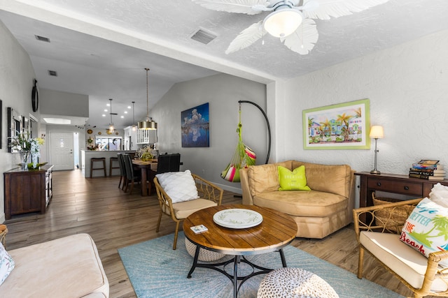 living room with hardwood / wood-style flooring, ceiling fan, lofted ceiling, and a textured ceiling