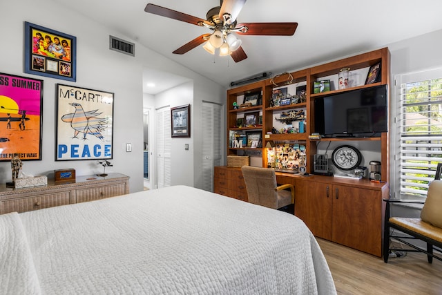 bedroom with vaulted ceiling, built in desk, ceiling fan, and light hardwood / wood-style flooring