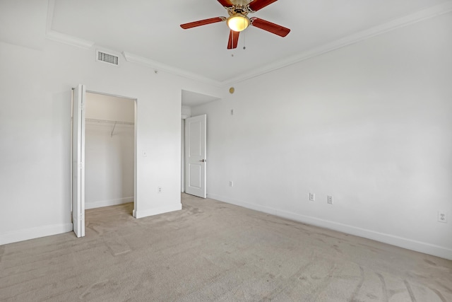 unfurnished bedroom with crown molding, light colored carpet, a closet, and ceiling fan