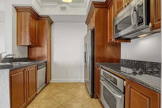 kitchen with light tile patterned floors, stainless steel appliances, sink, and dark stone countertops