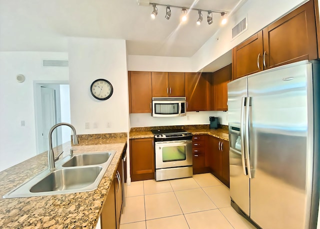 kitchen with light stone counters, stainless steel appliances, light tile patterned flooring, and sink