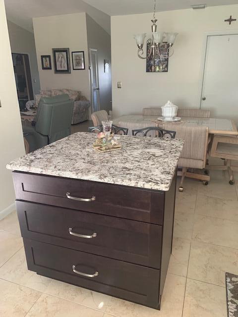 kitchen featuring light stone counters, a kitchen island, decorative light fixtures, and dark brown cabinets