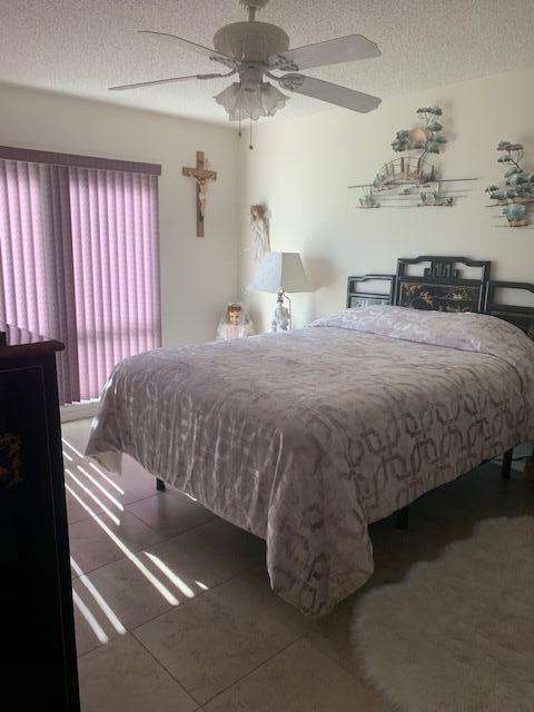 bedroom featuring ceiling fan, dark tile patterned flooring, and a textured ceiling