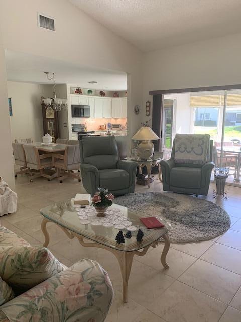 tiled living room with plenty of natural light and high vaulted ceiling