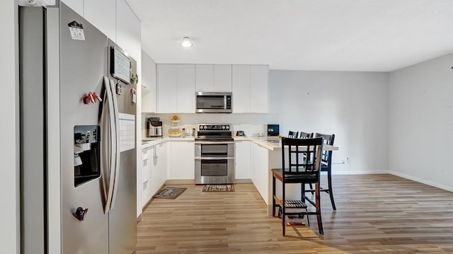 kitchen featuring light hardwood / wood-style flooring, stainless steel appliances, and white cabinets