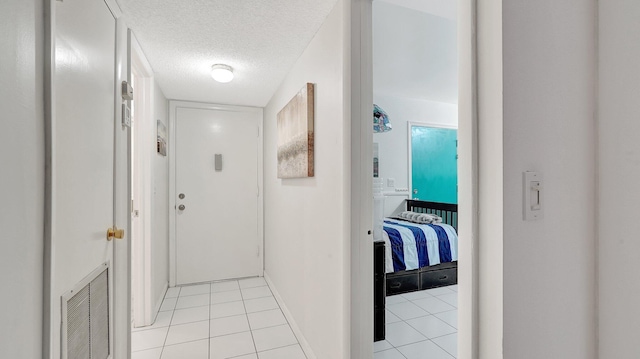 hallway with light tile patterned floors and a textured ceiling