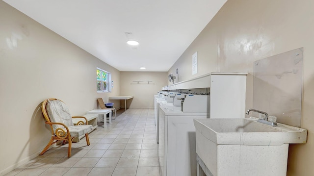 laundry area with light tile patterned floors, sink, and washing machine and clothes dryer