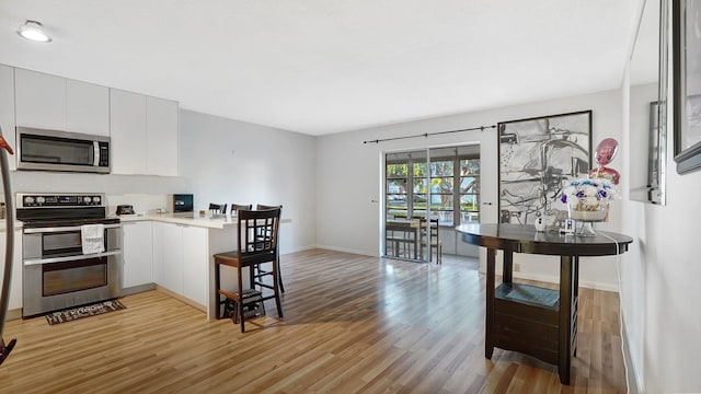 kitchen featuring french doors, white cabinetry, appliances with stainless steel finishes, and light hardwood / wood-style flooring