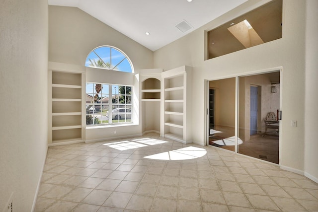 empty room with light tile patterned flooring, high vaulted ceiling, and built in shelves