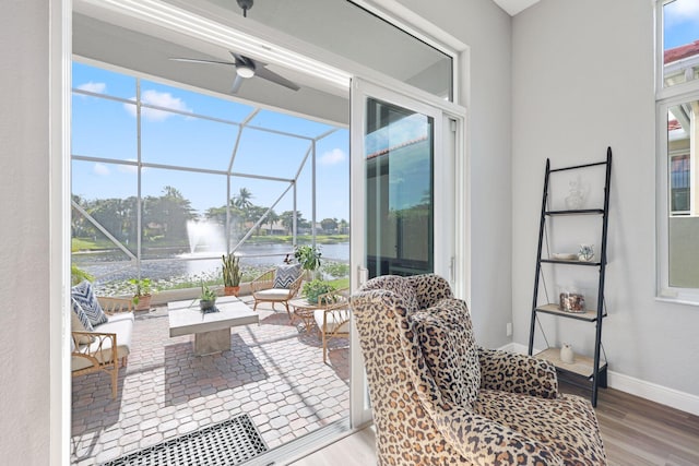 view of patio / terrace with a water view, ceiling fan, and a lanai