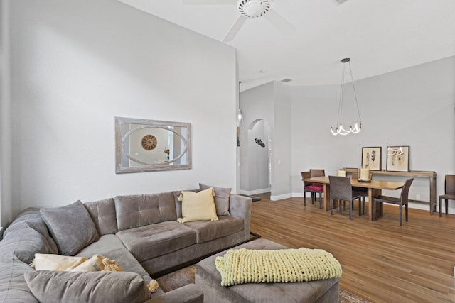 living room with hardwood / wood-style flooring and ceiling fan with notable chandelier