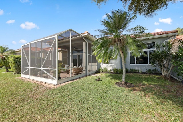 back of house with ceiling fan and a yard