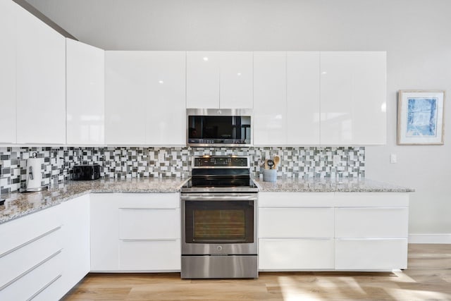 kitchen featuring light stone counters, appliances with stainless steel finishes, light hardwood / wood-style floors, decorative backsplash, and white cabinets