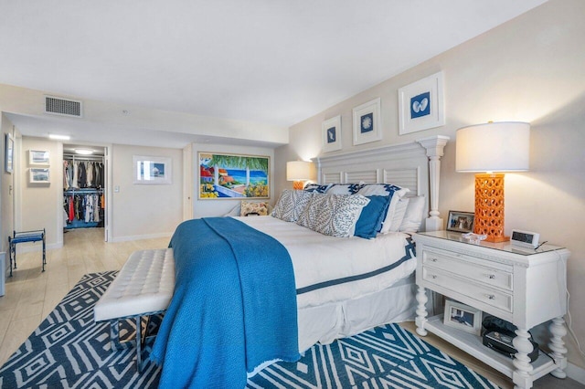 bedroom with a walk in closet, light hardwood / wood-style floors, and a closet