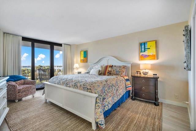 bedroom with floor to ceiling windows, access to outside, and light hardwood / wood-style flooring