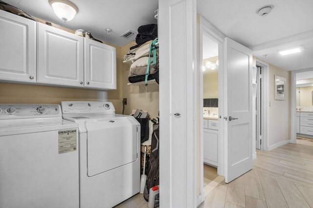 laundry room featuring cabinets, light hardwood / wood-style floors, and washer and dryer