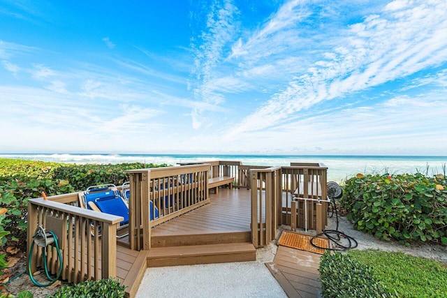 wooden terrace featuring a beach view and a water view