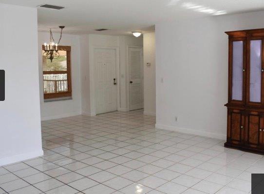 spare room featuring an inviting chandelier and light tile patterned floors