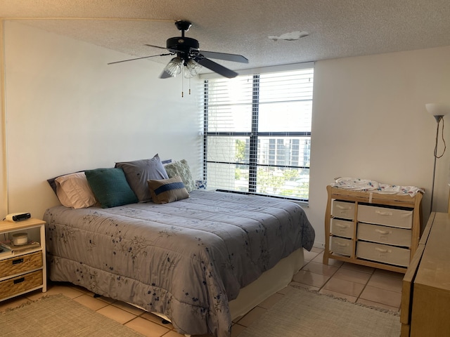 bedroom featuring light tile patterned floors, a textured ceiling, and ceiling fan