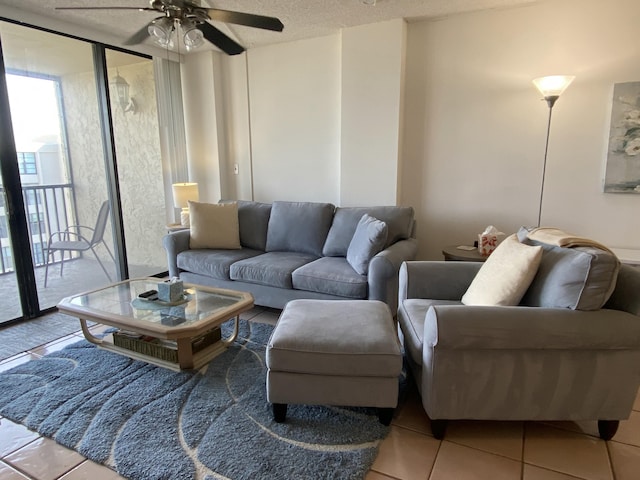 living room with tile patterned flooring, ceiling fan, a wall of windows, and a textured ceiling